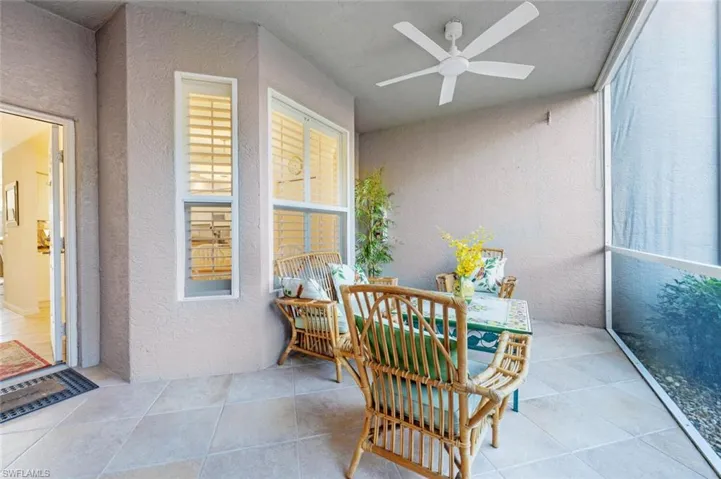Sunroom with a textured wall, a ceiling fan, and tile patterned flooring