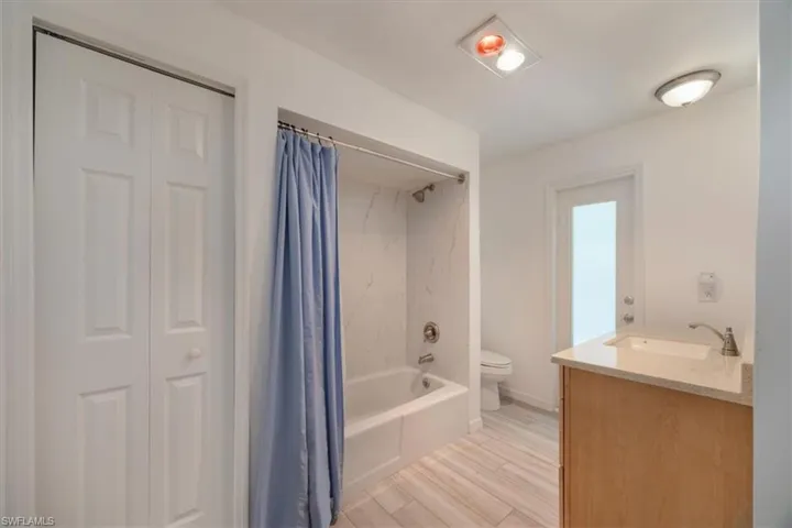 Guest bathroom featuring a closet, toilet, vanity, luxury vinyl floors, and shower / bath combination.