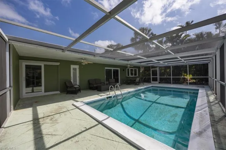 View of pool with bathroom access, screened enclosure and patio area.