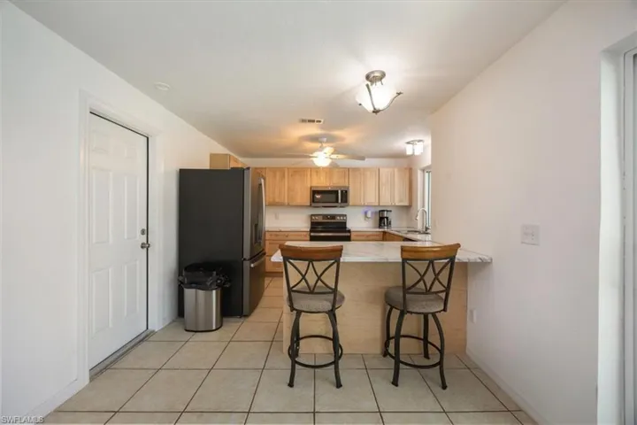 Kitchen with ceramic tile floor, new stainless steel appliances, new cabinets, and peninsular counter.