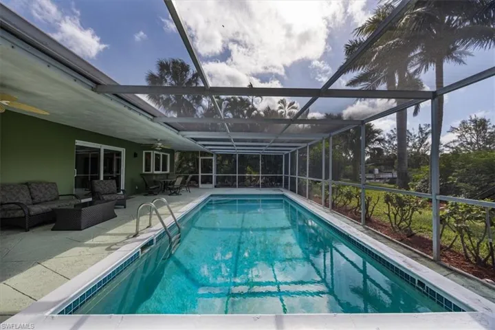 Outdoor pool with ceiling fan, screened enclosure, outdoor lounge area, and a patio.