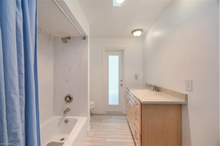 Guest bathroom with impact door leading to pool and luxury vinyl flooring.
