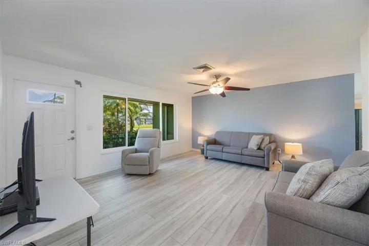 View of living room featuring luxury vinyl flooring, impact window and front door.
