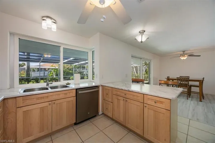 Kitchen with impact window leading to the pool area and stainless-steel dishwasher.