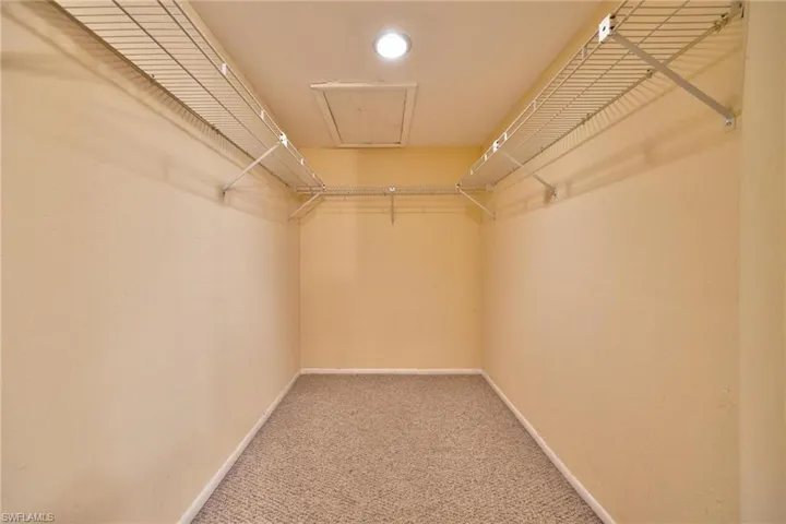 Walk in closet featuring carpet floors and attic access