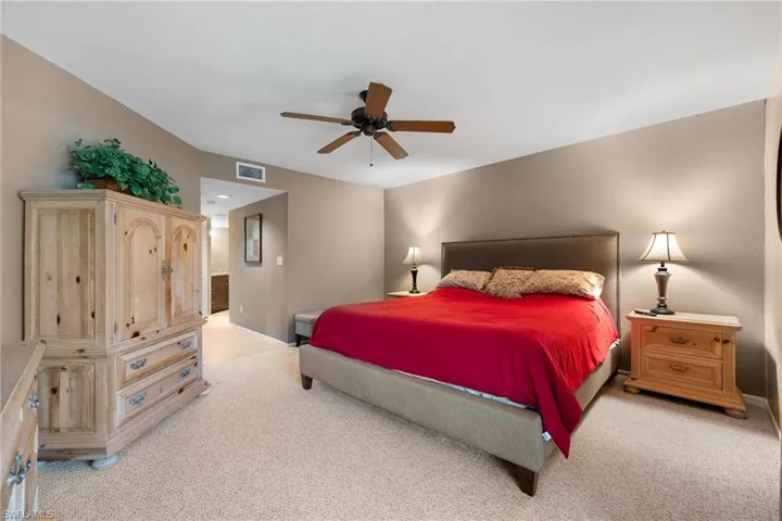 Bedroom with light carpet, ceiling fan, and ensuite bath