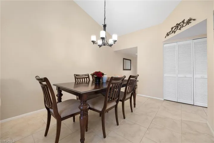 Dining area with a chandelier, light tile patterned floors, and high vaulted ceiling