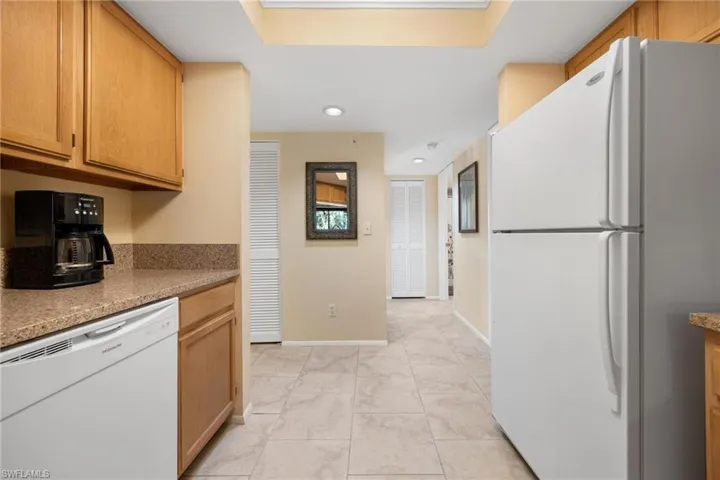 Kitchen featuring white appliances, light stone countertops, light tile patterned floors, and recessed lighting