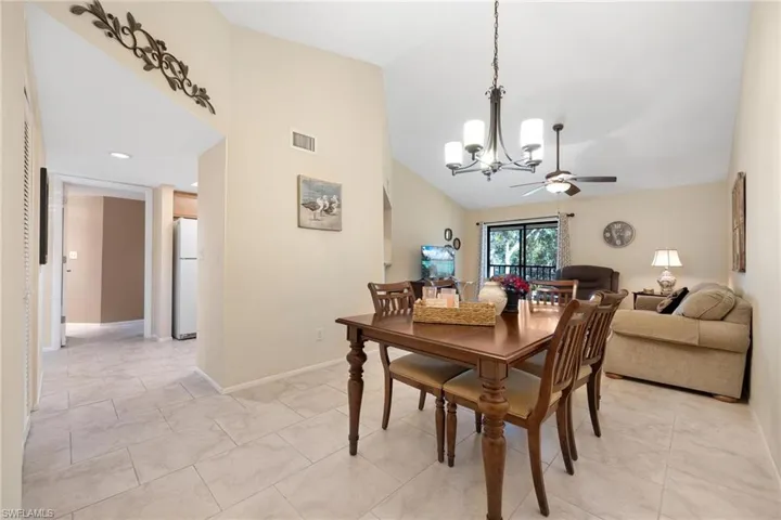 Dining room featuring a chandelier, lofted ceiling, ceiling fan, and light tile patterned floors