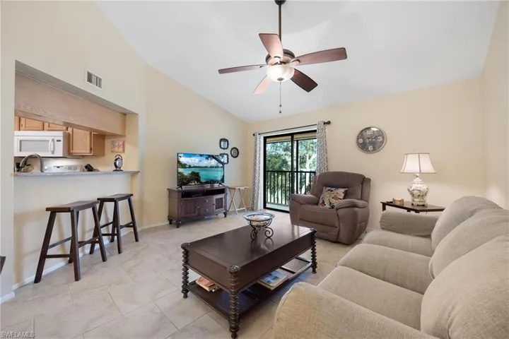 Living area with ceiling fan, light tile patterned floors, and high vaulted ceiling