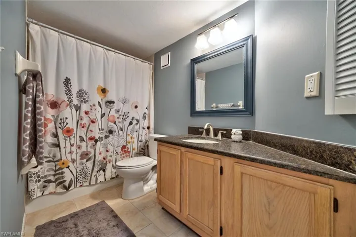 Bathroom with vanity, shower / bath combo with shower curtain, and light tile patterned floors