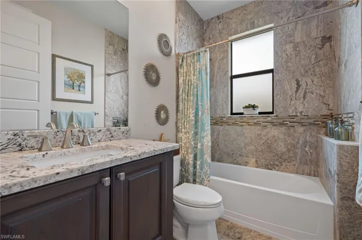 Full bathroom featuring tile flooring, large vanity, toilet, and shower / bath combo with shower curtain