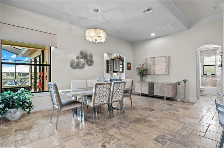 Tiled dining space featuring an inviting chandelier and crown molding
