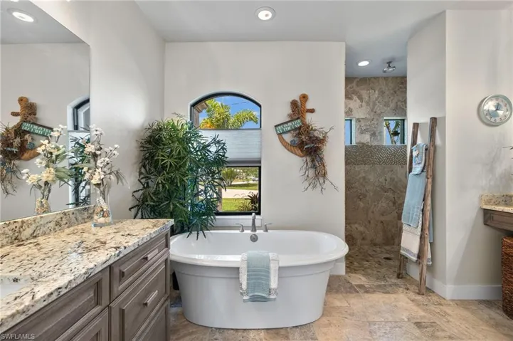 Bathroom with tile flooring, a bath to relax in, and vanity