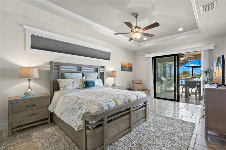 Bedroom featuring a tray ceiling, tile flooring, ceiling fan, and access to exterior