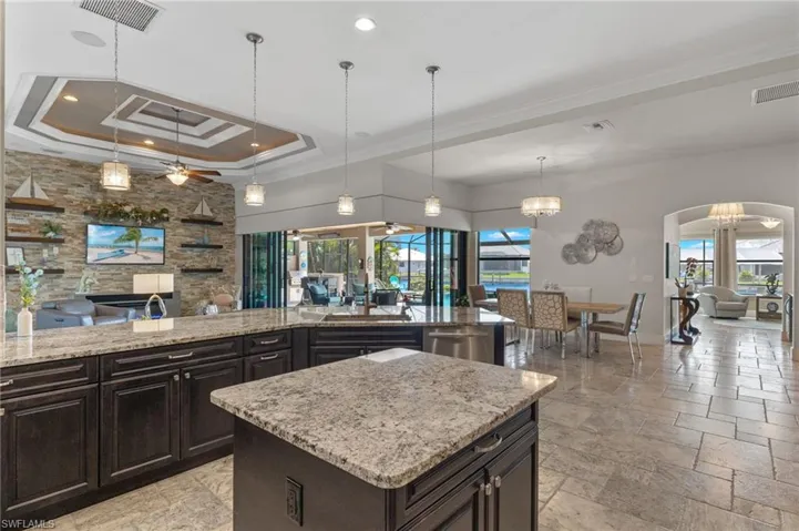 Kitchen featuring hanging light fixtures, a wealth of natural light, and ceiling fan with notable chandelier