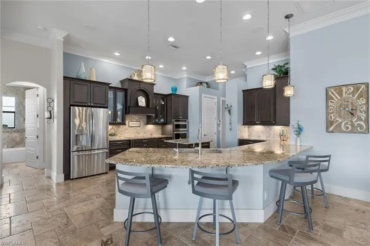 Kitchen featuring dark brown cabinetry, stainless steel appliances, tasteful backsplash, and decorative light fixtures
