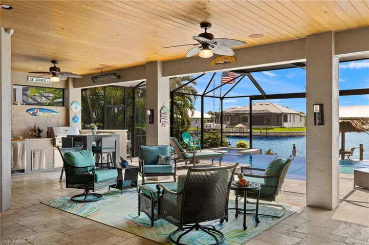 View of patio with ceiling fan, glass enclosure, a water view, and area for grilling