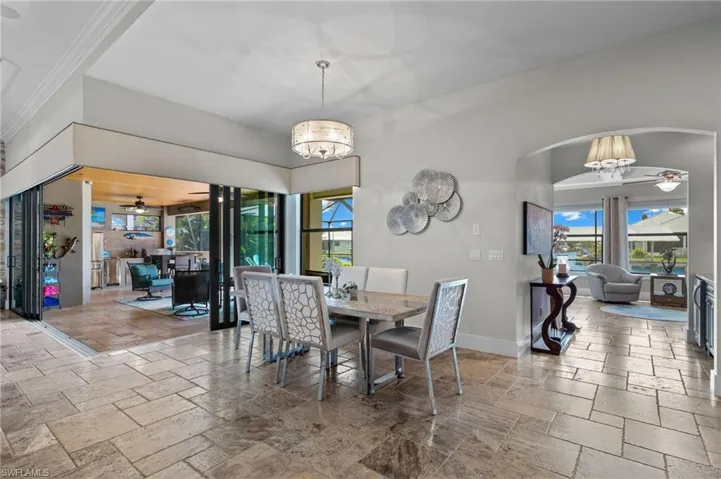 Dining space with tile flooring, plenty of natural light, and ceiling fan with notable chandelier