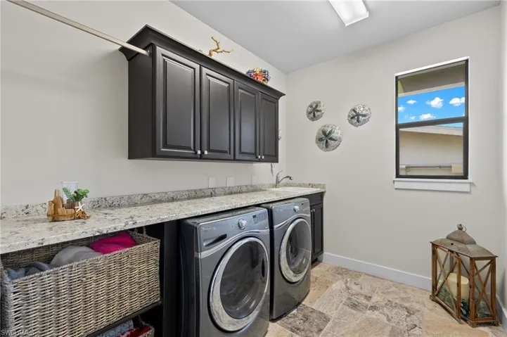 Washroom featuring cabinets, sink, light tile flooring, and separate washer and dryer