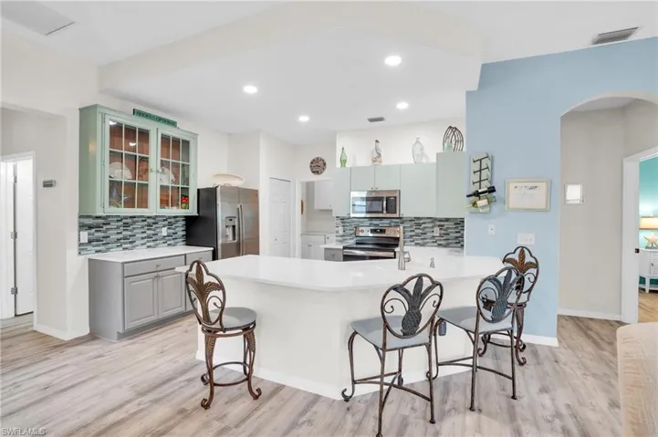 Kitchen featuring light wood-type flooring, kitchen peninsula, stainless steel appliances, and tasteful backsplash