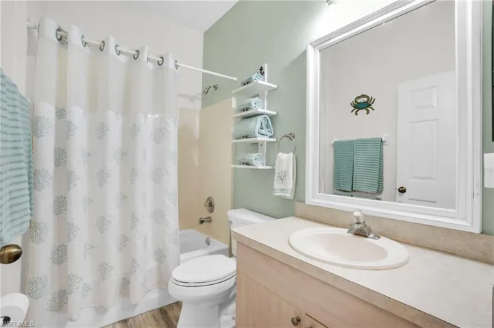 Full bathroom with vanity, wood-type flooring, shower / bath combo, and toilet