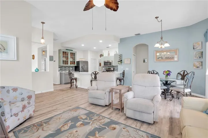 Living room featuring ceiling fan with notable chandelier and light wood-type flooring