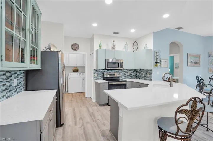 Kitchen with sink, a kitchen breakfast bar, independent washer and dryer, kitchen peninsula, and appliances with stainless steel finishes