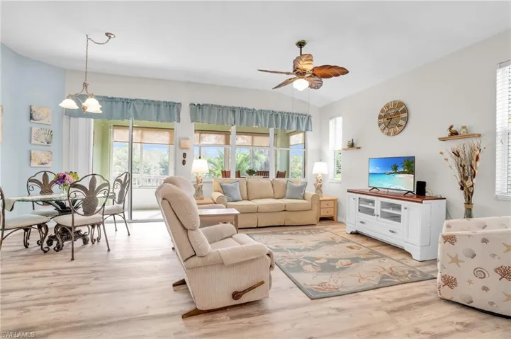 Living room featuring ceiling fan with notable chandelier, light hardwood / wood-style flooring, and a wealth of natural light