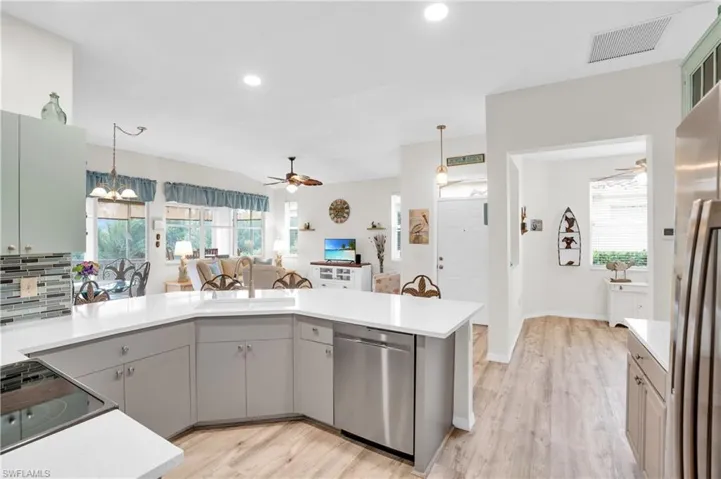 Kitchen with stainless steel appliances, hanging light fixtures, light hardwood / wood-style floors, and sink