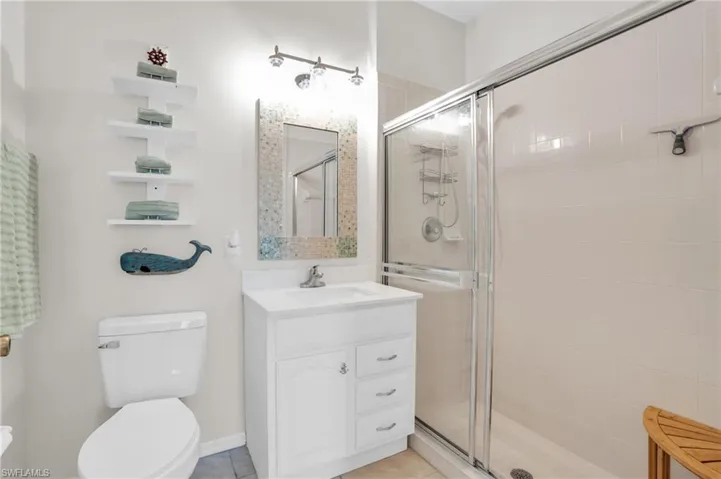 Bathroom featuring tile patterned flooring, vanity, toilet, and walk in shower