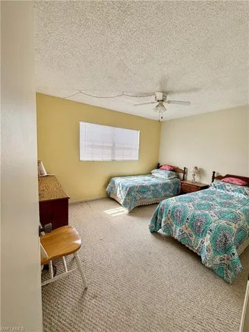 Carpeted bedroom featuring a textured ceiling and a ceiling fan