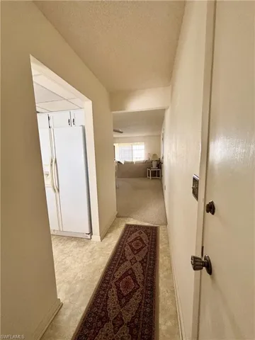 Hall with carpet and a textured ceiling