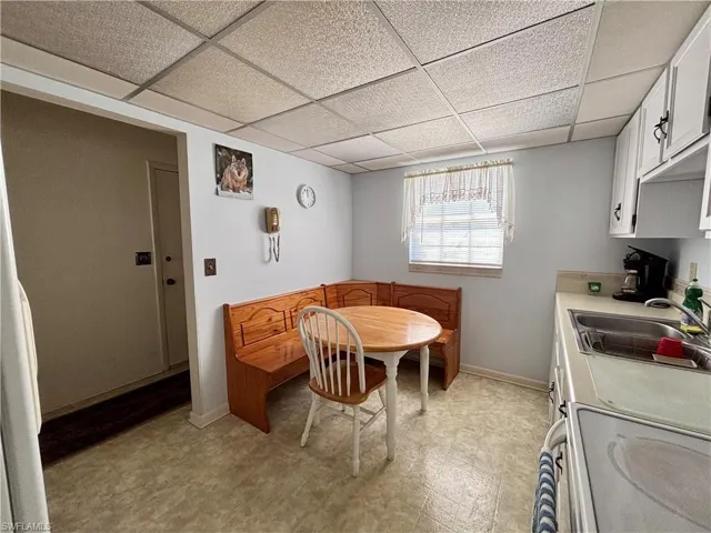 Dining space featuring a paneled ceiling, baseboards, and light floors