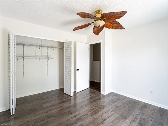 Unfurnished bedroom featuring dark wood-type flooring, a closet, ceiling fan, and a textured ceiling