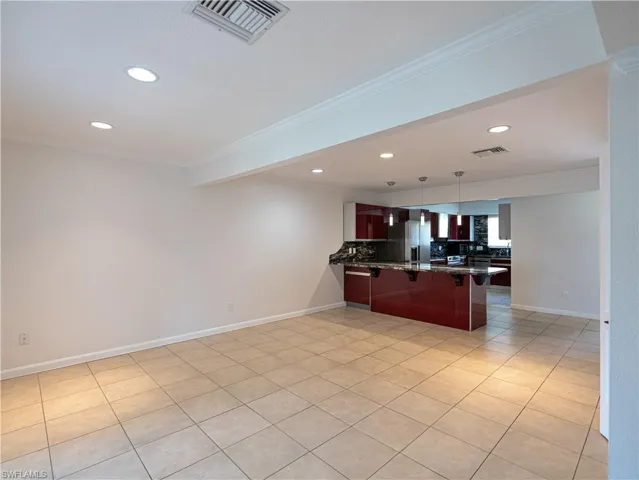 Kitchen with tile floors, kitchen peninsula, backsplash, and crown molding