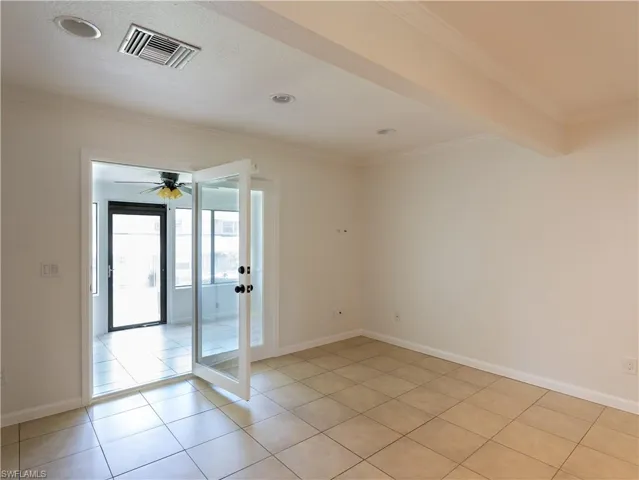 Spare room with beamed ceiling, ceiling fan, french doors, and light tile floors