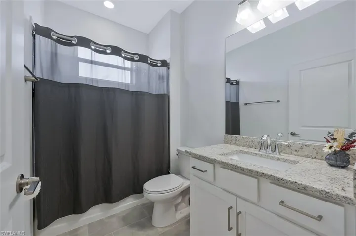 Bathroom with toilet, tile patterned floors, and vanity