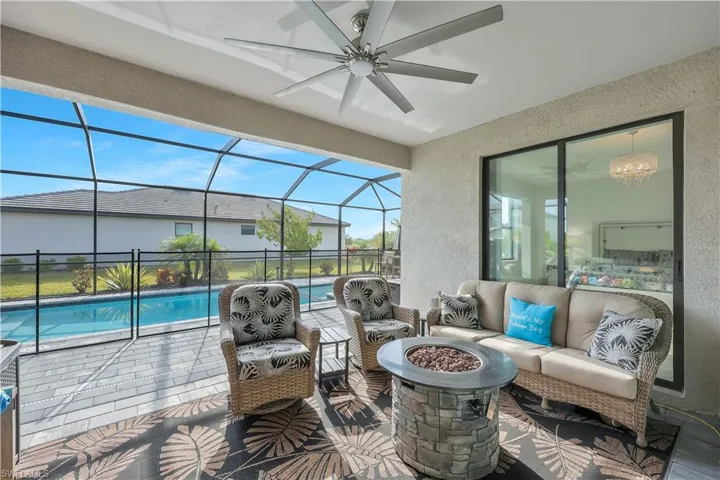 View of patio / terrace with glass enclosure, a fenced in pool, ceiling fan, and an outdoor living space with a fire pit
