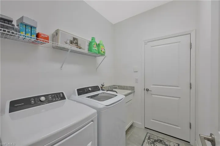 Washroom featuring light tile patterned floors, a sink, cabinet space, and separate washer and dryer