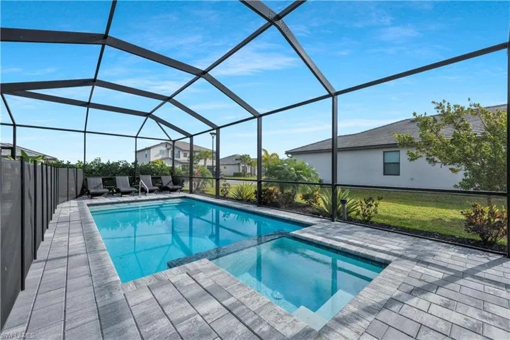 View of swimming pool featuring a pool with connected hot tub, glass enclosure, and a patio area