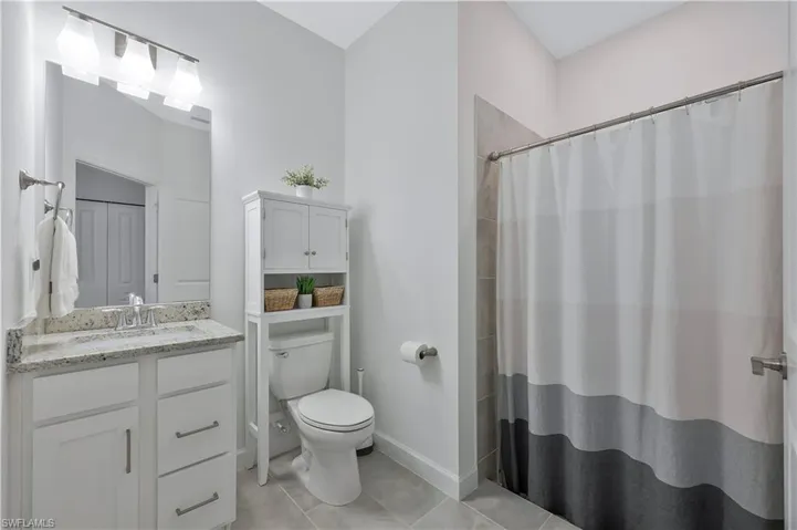 Full bath with curtained shower, toilet, tile patterned flooring, and vanity