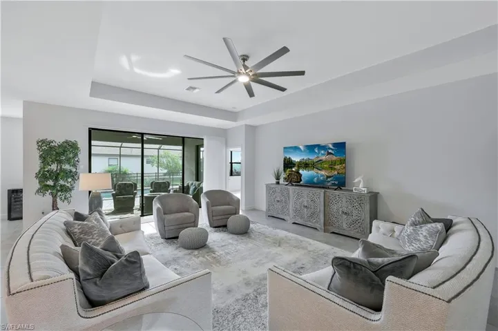 Living room with visible vents, ceiling fan, and a raised ceiling