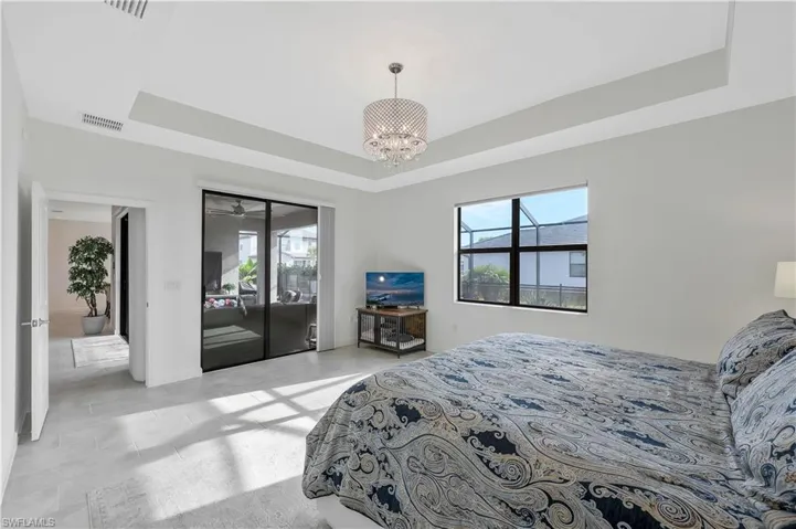 Bedroom featuring access to exterior, visible vents, multiple windows, and a raised ceiling