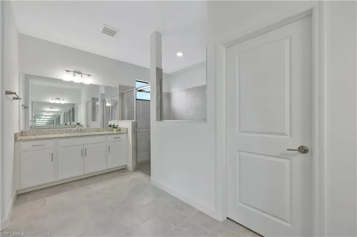 Bathroom with visible vents, a tile shower, and vanity