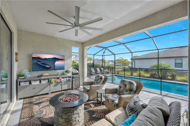 View of patio with a ceiling fan, an outdoor living space with a fire pit, a lanai, and an outdoor pool