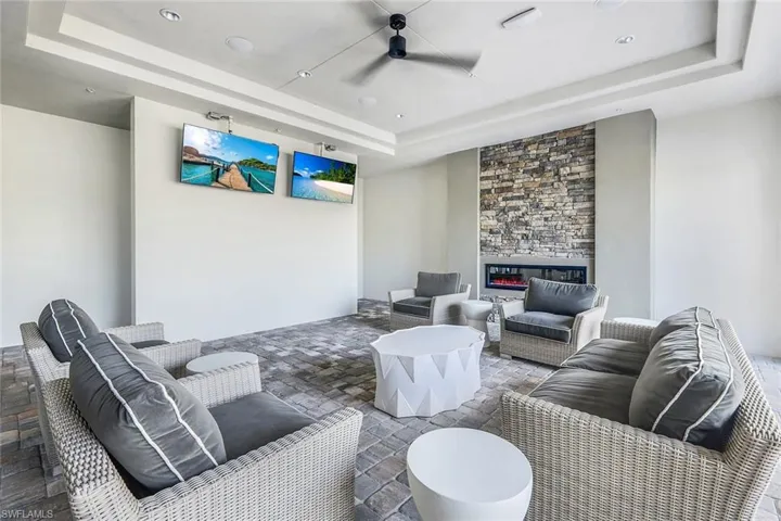 Living room with stone finish floor, a fireplace, a raised ceiling, and a ceiling fan