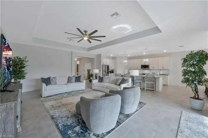 Living room featuring visible vents, a ceiling fan, and a raised ceiling