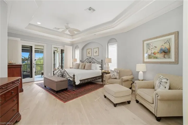 The incredible primary suite boasts a sitting area & a private lanai overlooking the canal & Imperial River beyond with an oversized custom outfitted walk-in closet & spa-like en-suite bath.