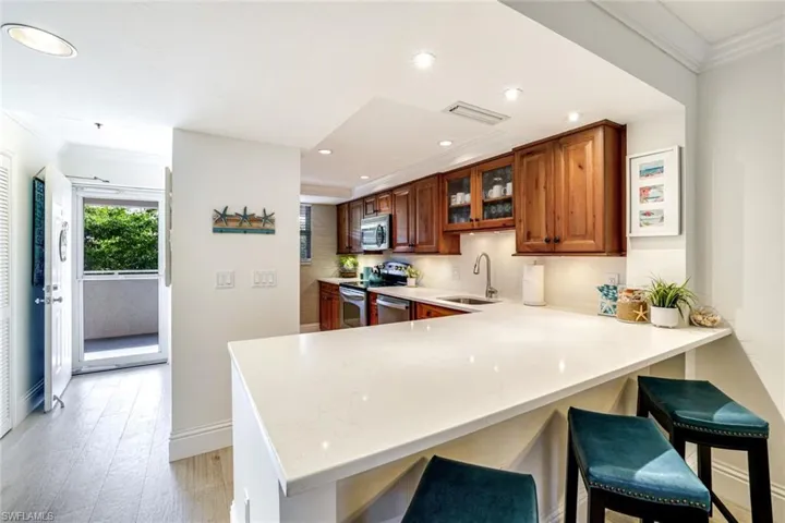 Kitchen with crown molding, a breakfast bar area, a peninsula, glass insert cabinets, and stainless steel appliances
